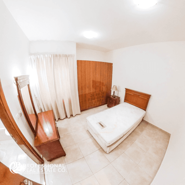 Spacious second bedroom in semi-furnished 2 BHK apartment in Al Sadd, perfect for family living