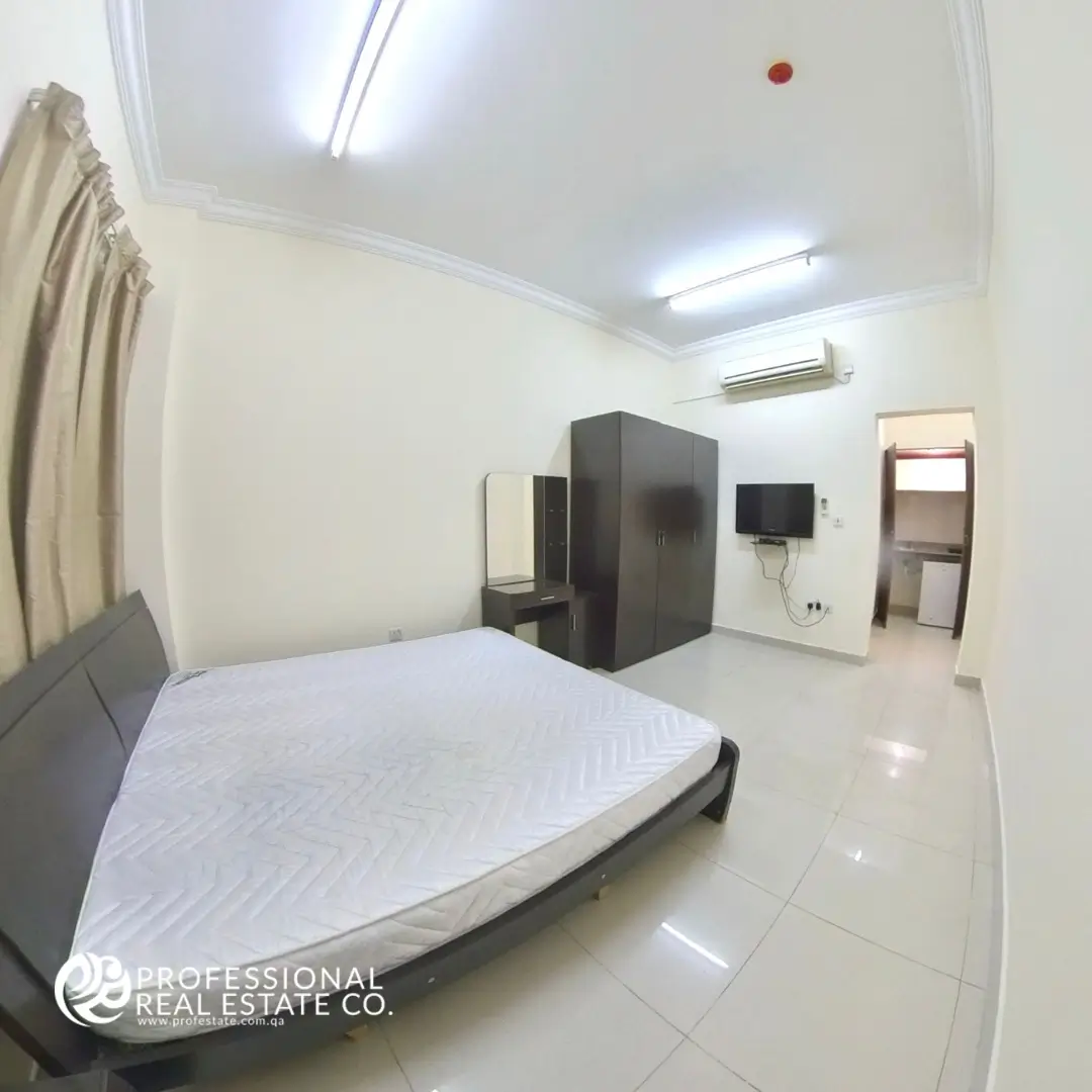 Another view of the fully furnished sleeping area in studio apartment for rent in Bin Mahmoud, Doha – Cozy bed, stylish decor, and natural light