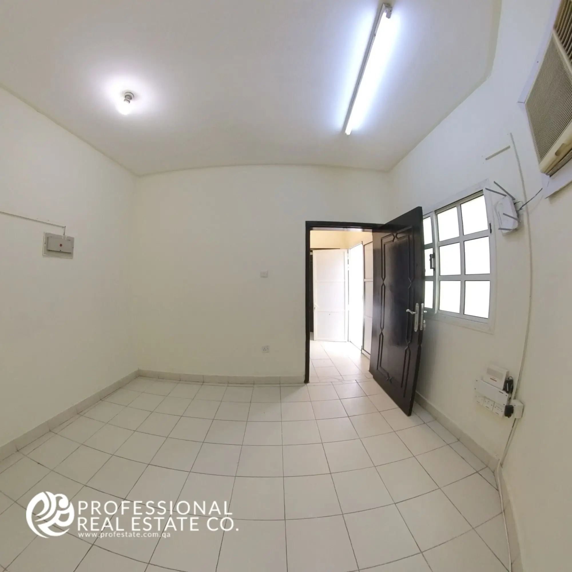 Another angle of the spacious living room in an unfurnished 1 BHK apartment for rent in Umm Lekhba, offering a clear view of the entrance door and an open, versatile layout.