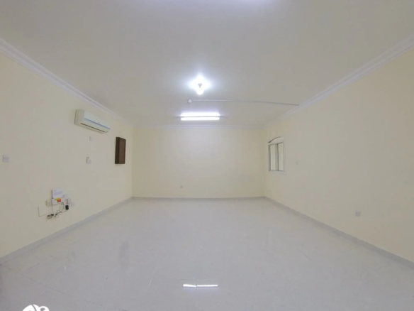 Spacious living room in an unfurnished 2 BHK apartment in Al Gharrafa, offering a versatile space ready for customization.