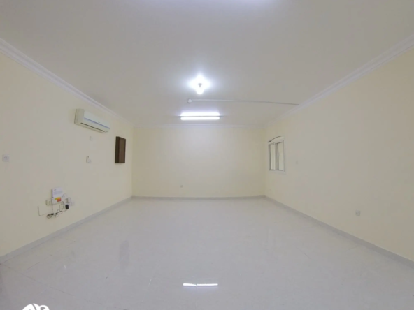 Spacious living room in an unfurnished 2 BHK apartment in Al Gharrafa, offering a versatile space ready for customization.