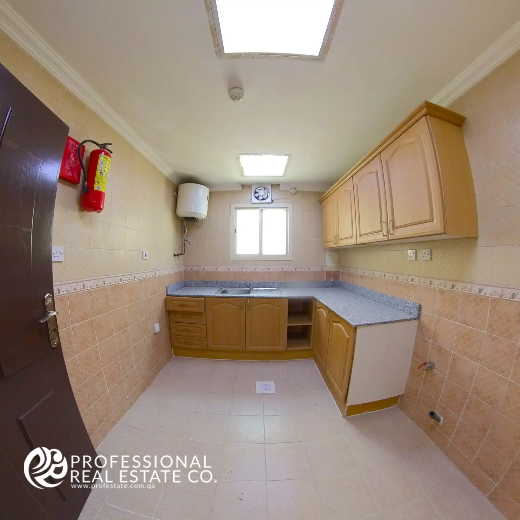 Closed kitchen with cabinetry and countertop in an unfurnished 2 BHK apartment in Al Sadd, Doha