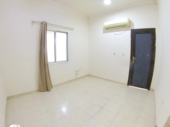 Bright and spacious bedroom in an unfurnished studio apartment for rent in Al Gharrafa, featuring a window and neutral walls for easy personalization.
