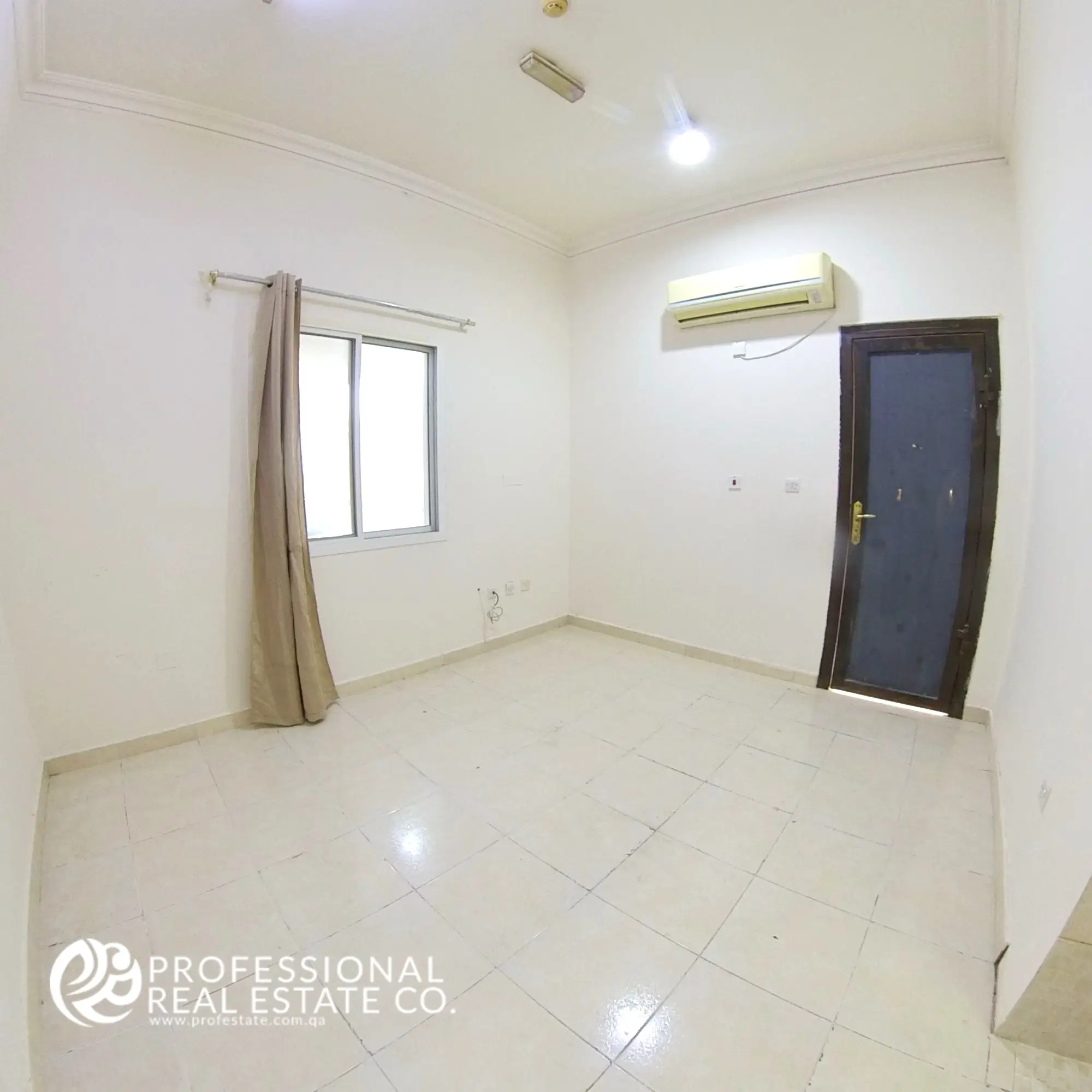 Bright and spacious bedroom in an unfurnished studio apartment for rent in Al Gharrafa, featuring a window and neutral walls for easy personalization.