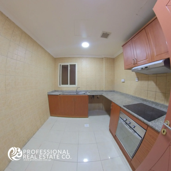 Closed kitchen with built-in cabinets and tiled walls in a semi-furnished 2 BHK apartment for rent in Muntazah, Doha