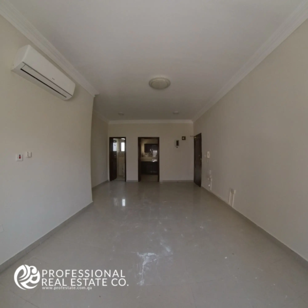 "Living room view facing closed kitchen and guest toilet door in an unfurnished 2 BHK apartment in Muntazah, Doha