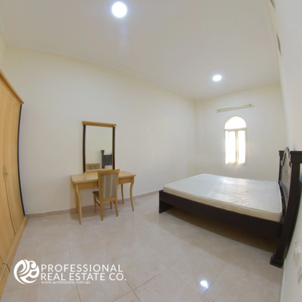 Alternative view of the spacious master bedroom with natural light and neutral finishes in a semi-furnished 2 BHK apartment in Muntazah, Doha