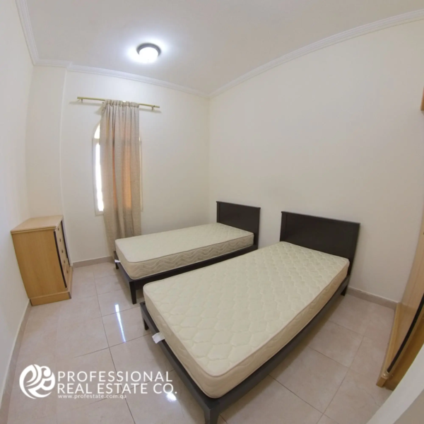 Bedroom with two single beds and natural light in a semi-furnished 2 BHK apartment for rent in Muntazah, Doha