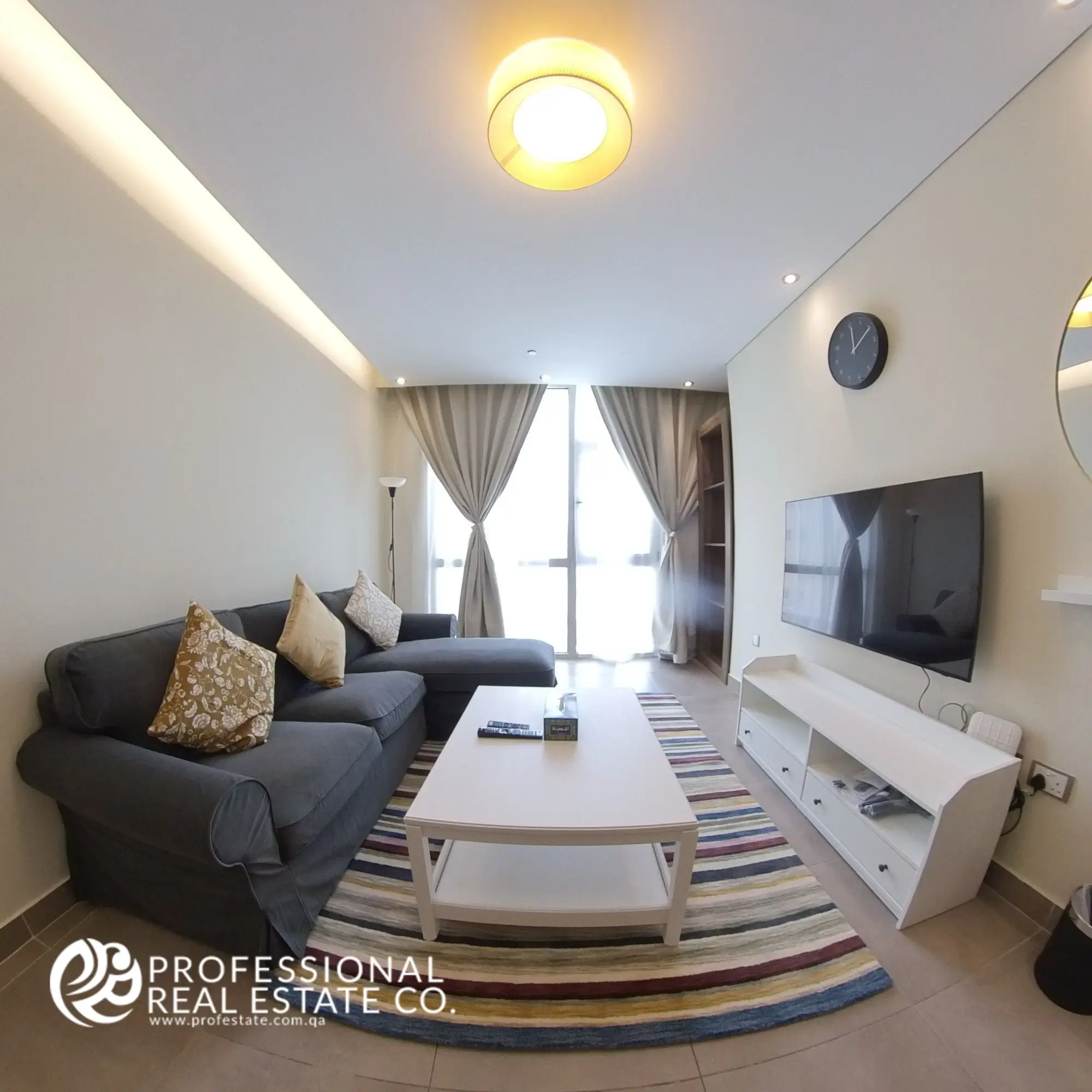 Alternative view of the living room showcasing the window side in a fully furnished 1 BHK apartment in Al Sadd, emphasizing natural light and open space.