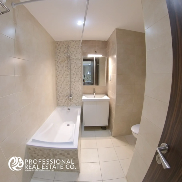 Toilet with bathtub and shower in a fully furnished 1 BHK apartment in Al Sadd, offering a relaxing and modern bathroom design.