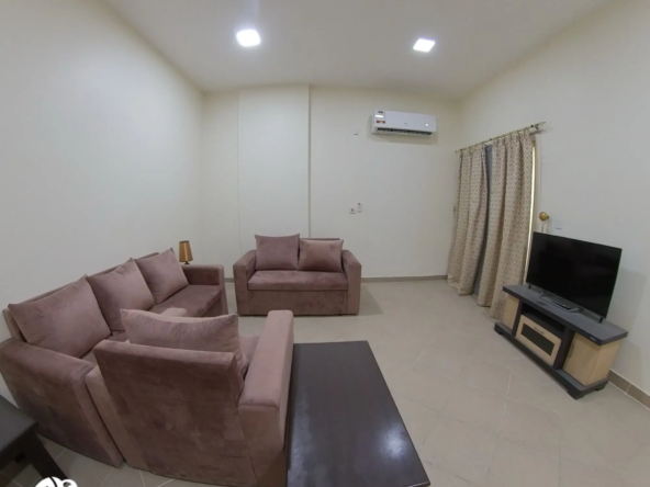 Living room with modern furnishings and natural light in a fully furnished 2 BHK apartment in Bin Mahmoud, Doha
