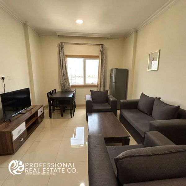 Another angle of the living and dining area with window side in a fully furnished 1 BHK apartment in Umm Ghwailina, highlighting layout, furniture, and natural light.